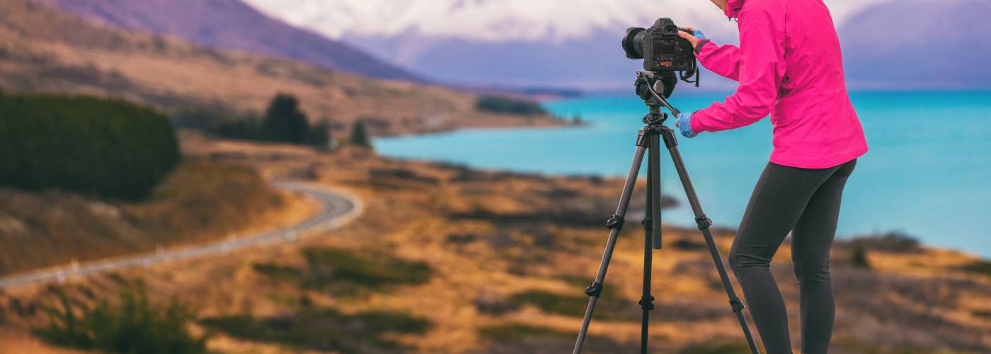 Person fotografiert Landschaft mit Stativ